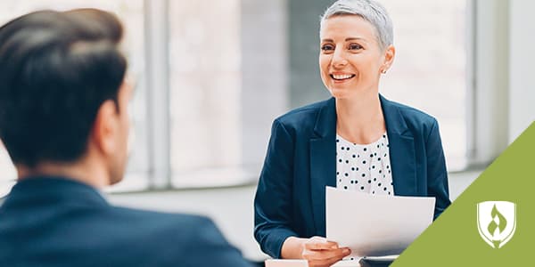 Image depicts professionally-dressed man and woman discussing a work matter.