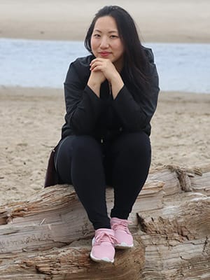 woman sitting on log at beach