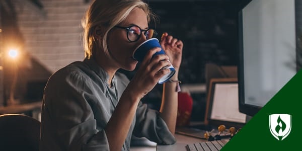 female designer drinking from a mug while looking at her computer screen
