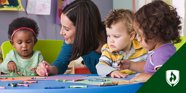 Photo of an adult interacting with preschoolers who are coloring and asking questions.