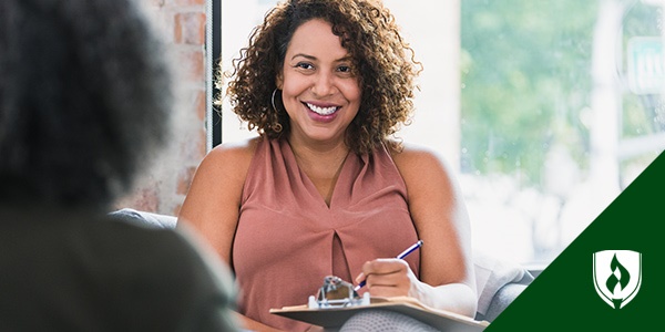 photo of a human services professional smiling at a client and writing on a clipboard