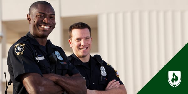 Two smiling police officers with their arms crossed.
