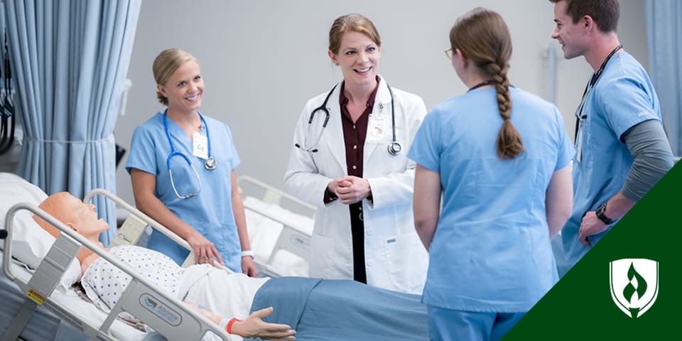 Photo of three nursing students listening to a nursing instructor .