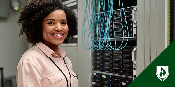 A female network administrator standing in front of a server cluster