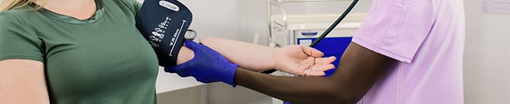 female medical assistant taking blood pressure of female patient