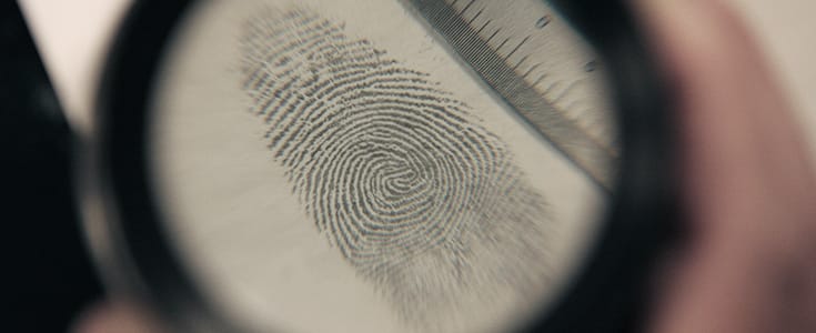 Photo of a magnifying glass examining a finger print.