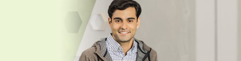 man leaning on desk in office smiling at camera