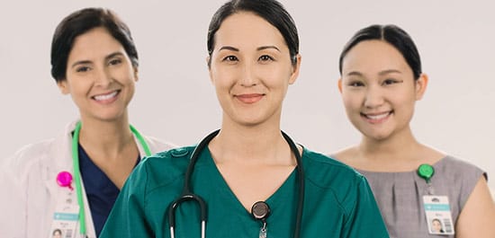 team of smiling female healthcare professionals in lab coat and scrubs with stethoscope and dress