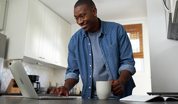 Smiling man standing in front of laptop on a counter