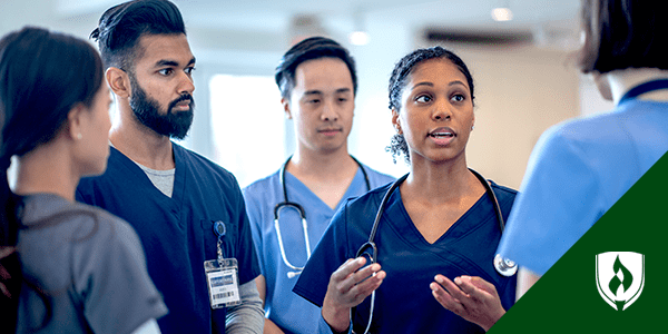 A dark-skinned female nurse instructs four other nurses during national nurses week