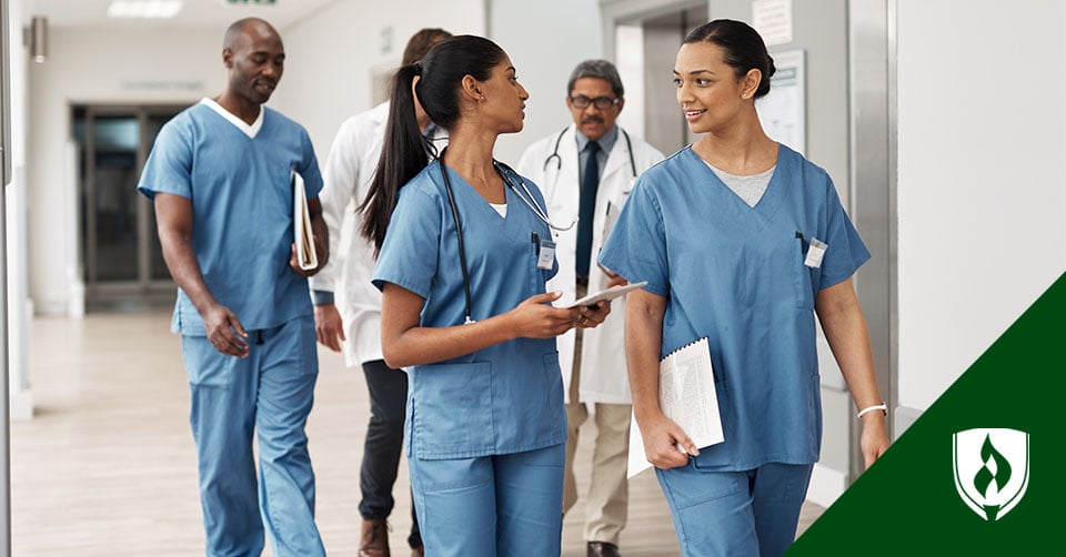 Three RNs walk down a hall with two doctors in conversation