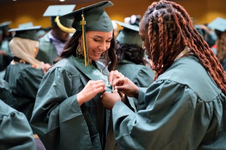Smiling Rasmussen University graduates pinning each other