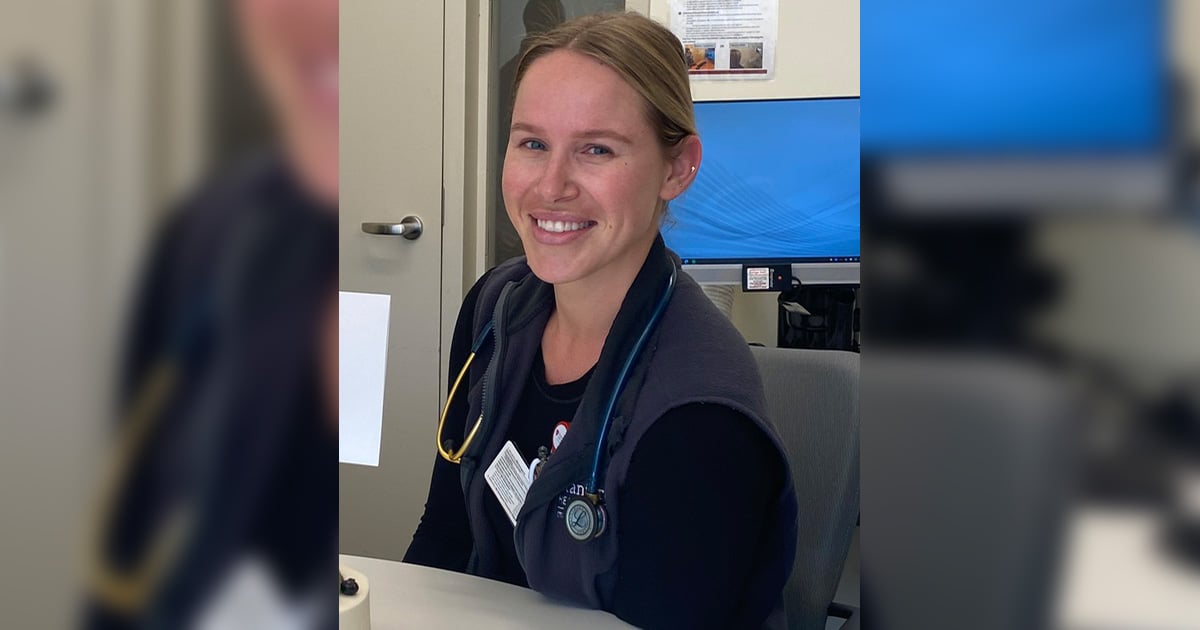 smiling female trauma nurse sitting at table with stethoscope around neck