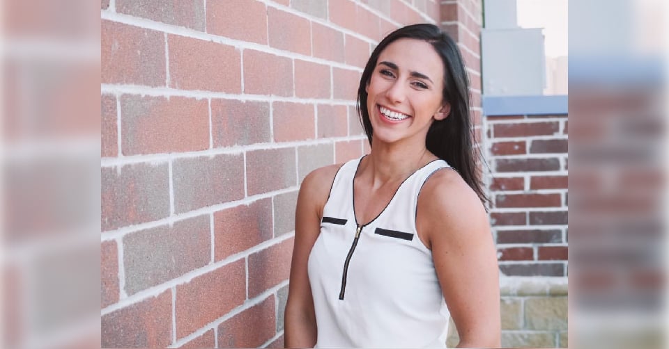 Rebecca Modeen smiles next to a brick wall outdoors