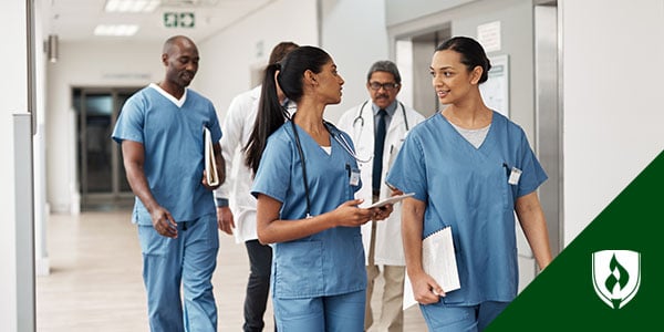 Three RNs walk down a hall with two doctors in conversation