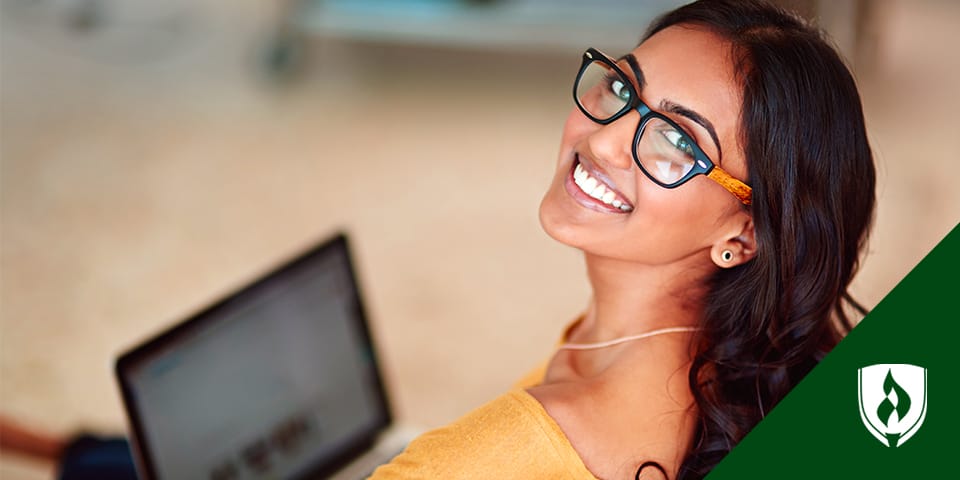 photo of an online student smiling at the camera with a laptop
