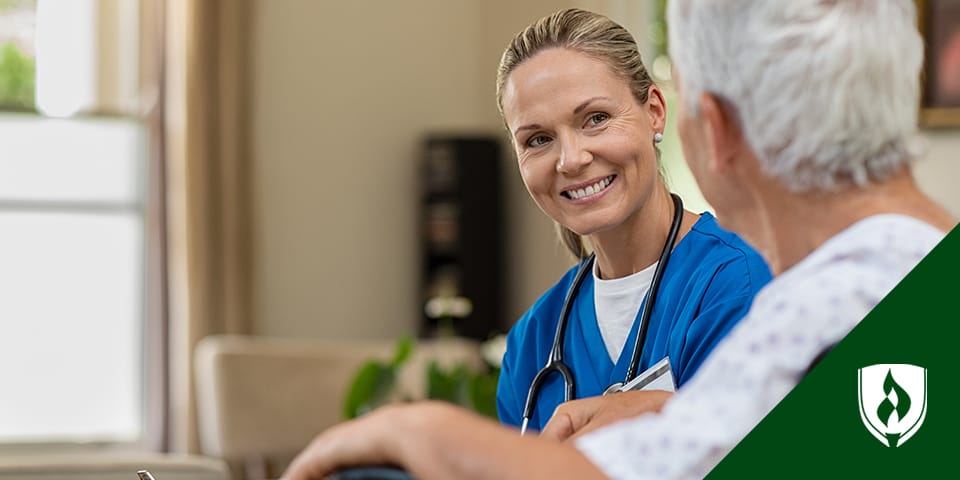 Blonde female nurse smiling and talking with elderly patient.