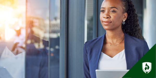 A business professional stands next to a bright window
