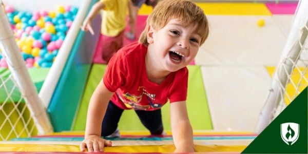 A laughing child climbs an indoor play structure