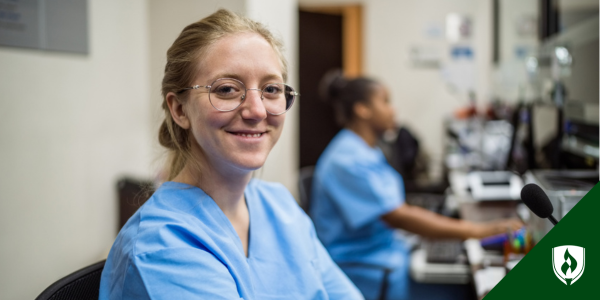 Medical receptionist in blue scrubs sits in a medical office