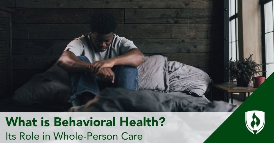 behavioral header A man sits on his bed in a shadowed room looking lost