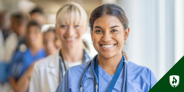 BSN nurse smiles in front of a line of healthcare workers
