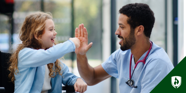 A nurse smiles and high fives a kid
