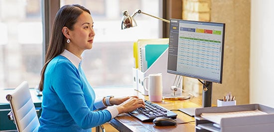 woman at desk looking at computer screen showing chart