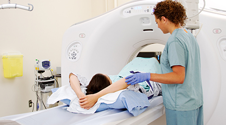 female technician adjusting patient in CT scanner