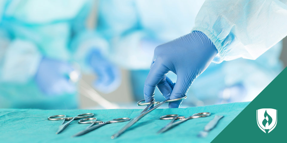hand in a medical glove grabbing a surgical scissors