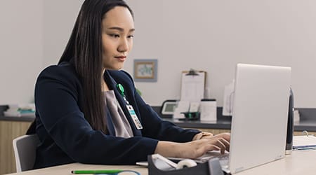 female healthcare professional working at her desk laptop