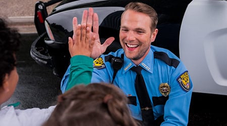 male officer giving a high-five to small children