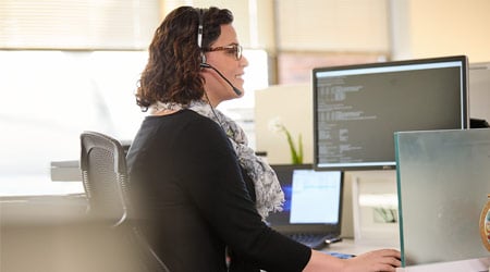 female technician talking on headset in front of computer