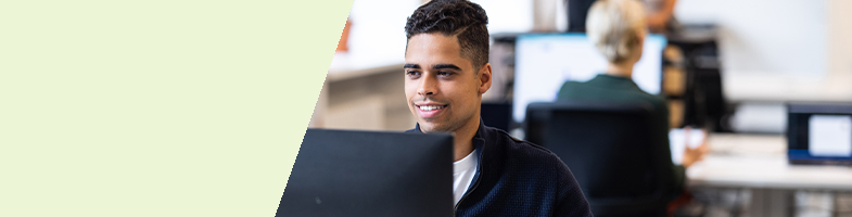 Information Technology professional sitting at a desk in front of a computer in an office setting