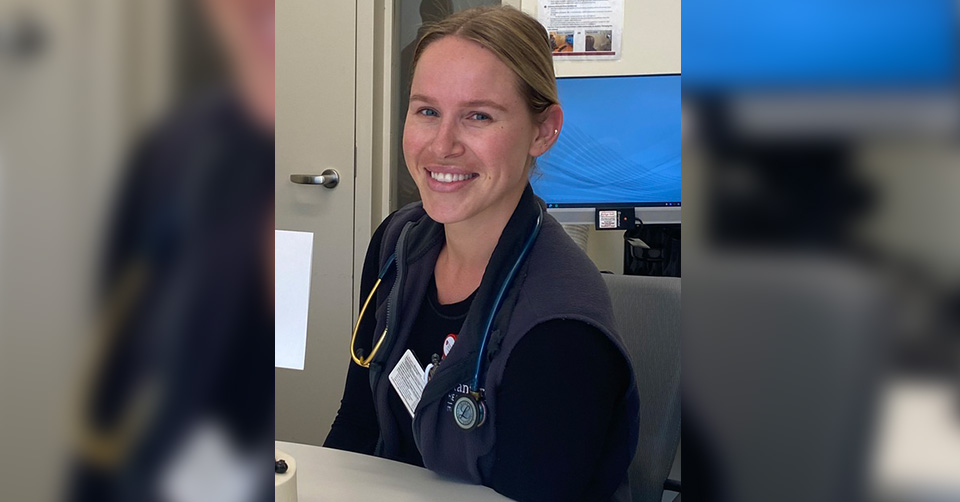 smiling female trauma nurse at table with stethoscope around neck