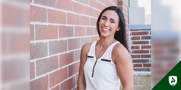 Rebecca Modeen smiles next to a brick wall outdoors